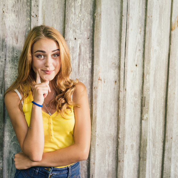 Fashion young blonde woman in yellow Tshirt over pale wooden background - Photo, image