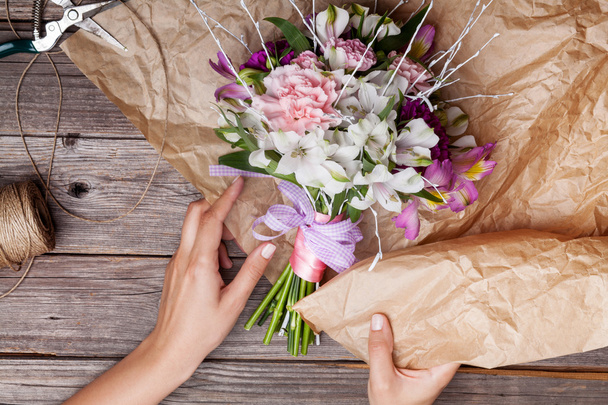 Packing a rustic bouquet from gillyflowers and alstroemeria on o - Foto, afbeelding
