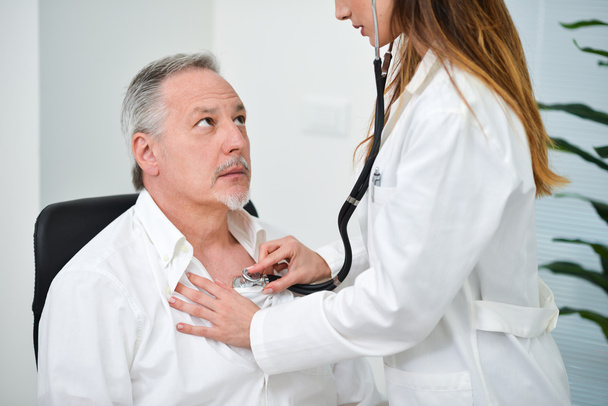 Doctor hearing patient's heartbeat - 写真・画像