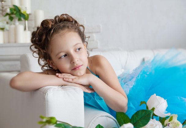 Little girl in blue dress lying on the sofa - Фото, изображение