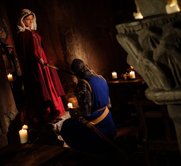 Middeleeuwse koningin doen knighting ceremonie in oude kasteel-interieur. - Foto, afbeelding