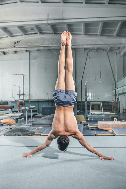 caucasian man gymnastic acrobatics equilibrium posture at gym background - Fotoğraf, Görsel