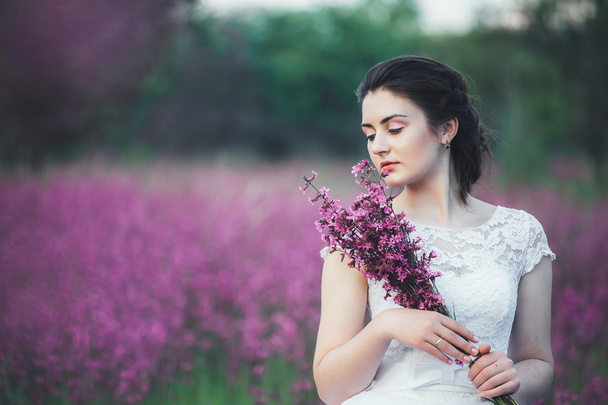 красива наречена в квітковому полі. Дівчина в білій сукні з букетом в літньому полі на заході сонця
 - Фото, зображення