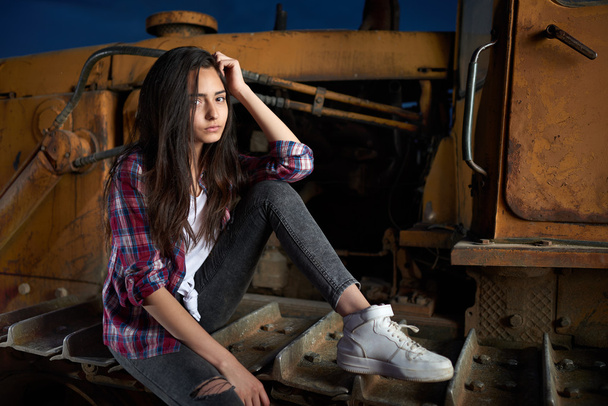 beautiful teen girl sitting on an old tractor - 写真・画像