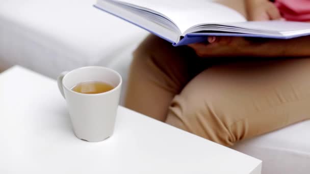 african woman reading book and drinking tea - Záběry, video