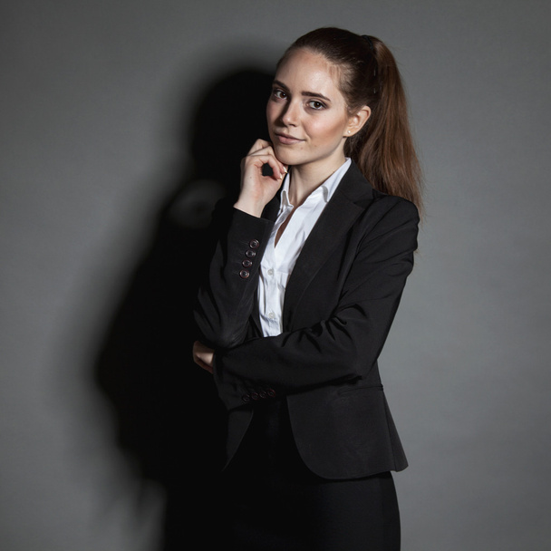 Portrait of young businesswoman in black suit on dark background - Fotografie, Obrázek