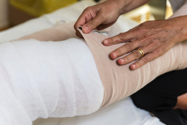 Woman bandaging patient's legs - Foto, afbeelding
