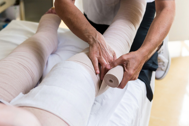 Woman bandaging patient's legs - Photo, Image