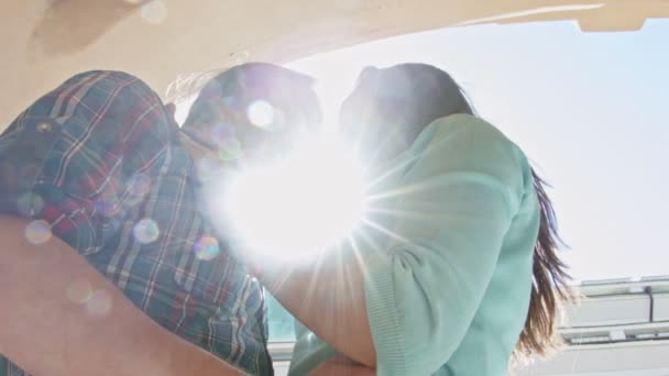 Ładna dziewczyna i chłopak z długimi włosami, w ciemnych okularach pocałunki na ulicy przed słońcem - Materiał filmowy, wideo