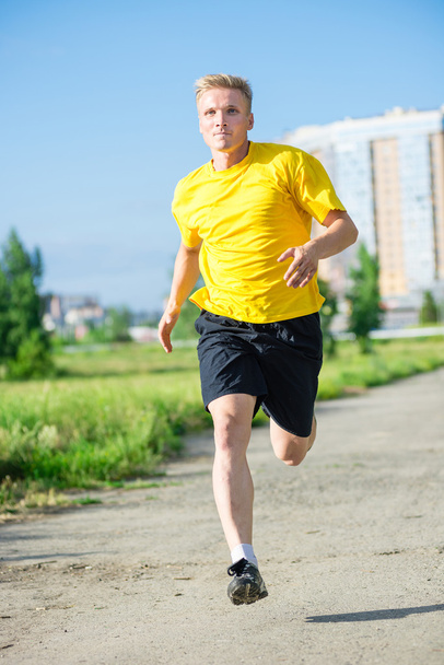 Sporty man jogging in city street park. Outdoor fitness. - Фото, изображение