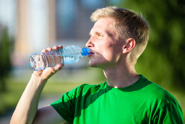 Уставший человек пьет воду из пластиковой бутылки после фитнеса
 - Фото, изображение