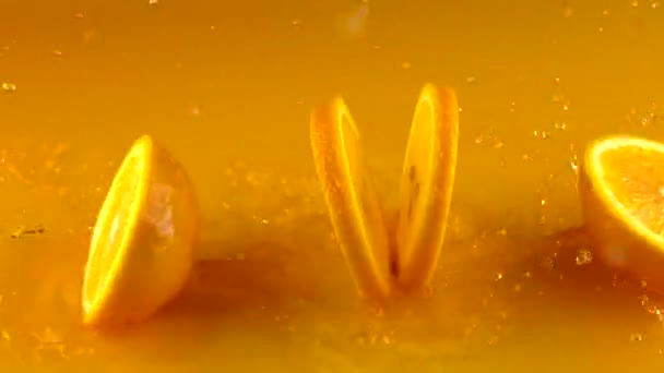 Cut ripe orange hits orange juice surface and rebounces. Slow motion video - Felvétel, videó