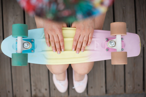 Girl holds colorful short cruiser skateboard deck - Foto, afbeelding