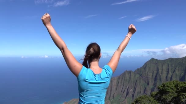 Pomalý pohyb: hrdá mladá žena na vrcholku hory vesele přetáhla ruce - Záběry, video
