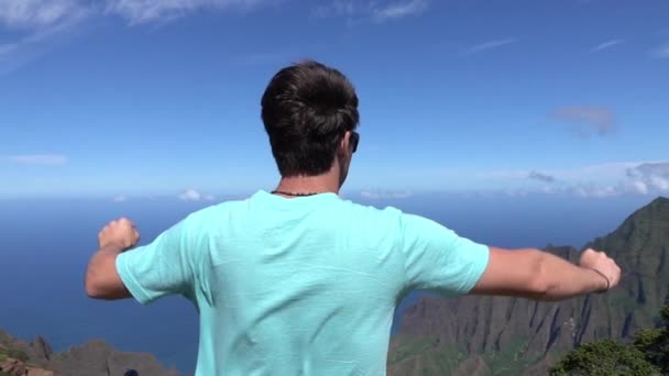 Lassú mozgás: vidám fiatalember a hegytetőn outstretching karok büszkén - Felvétel, videó