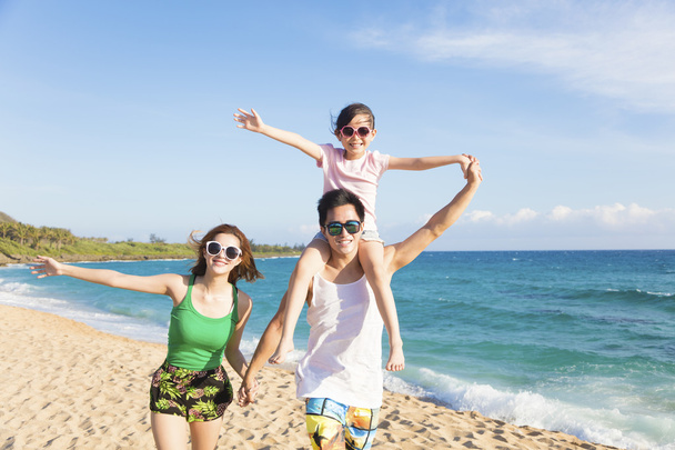 Χαρούμενη νεαρή οικογένεια περπατά στην παραλία - Φωτογραφία, εικόνα