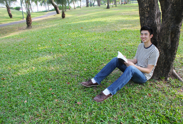 Young man reading the book in the park - Foto, afbeelding