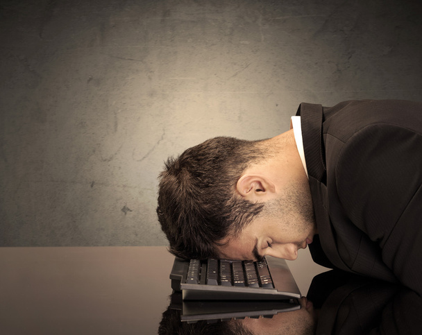 Frustrated businessman's head on keyboard - Фото, изображение