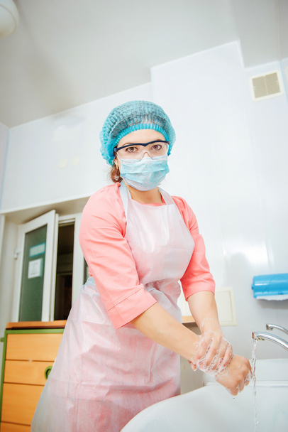 female surgeon putting on gloves before surgery - Foto, imagen