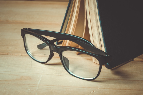 Old books and glasses on a wooden table with filter effect retro - Foto, imagen