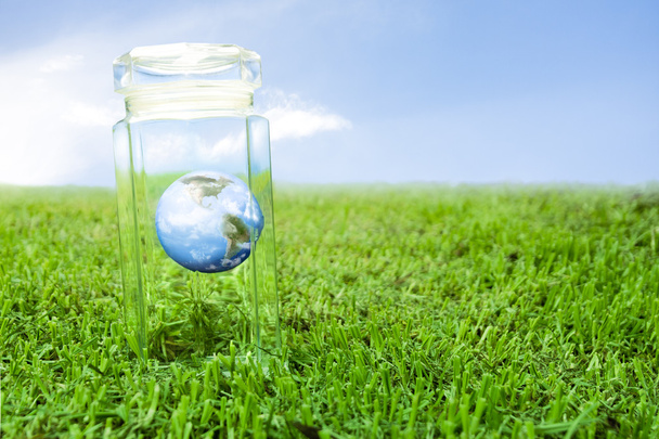 Proteger la tierra dentro de un frasco de cristal sobre hierba, ideal para el fondo
 - Foto, Imagen