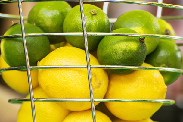 Limões e limas verdes na cesta de metal
 - Foto, Imagem