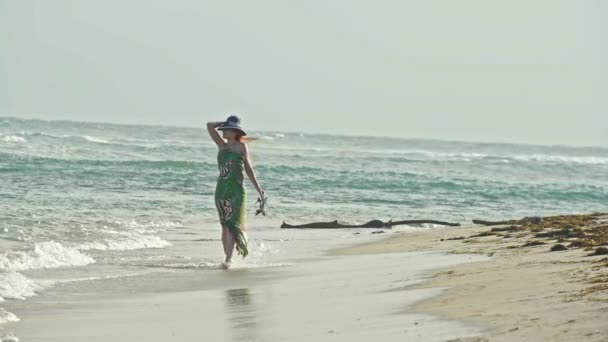 Jeune femme en robe longue tenir un chapeau et marcher le long de la mer, au ralenti
 - Séquence, vidéo