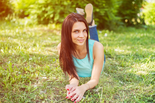 Beautiful woman relaxing outdoors on grass looking happy and smiling. - Foto, Bild