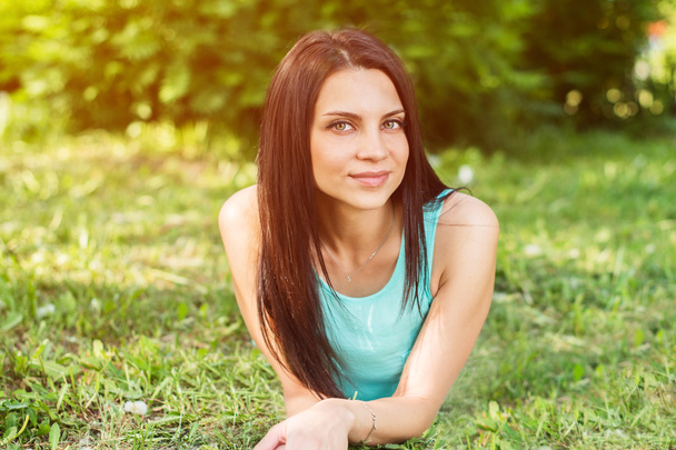 Piękna kobieta, relaks na świeżym powietrzu, na trawie patrząc szczęśliwa i uśmiechnięta. - Zdjęcie, obraz