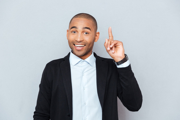 Portrait of a happy young man pointing finger up - Photo, image