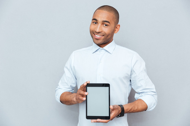 Smiling attractive african american young man holding blank screen tablet - Foto, Imagem