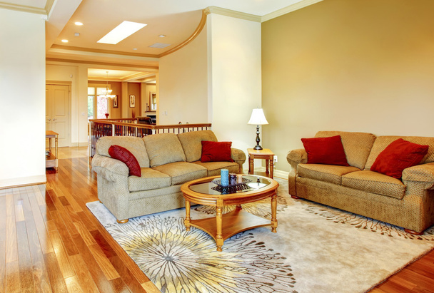 Jasny brązowy i czerwony salon wnętrze z drewnianą podłogą, ładny dywan i drewniany stolik.  - Zdjęcie, obraz