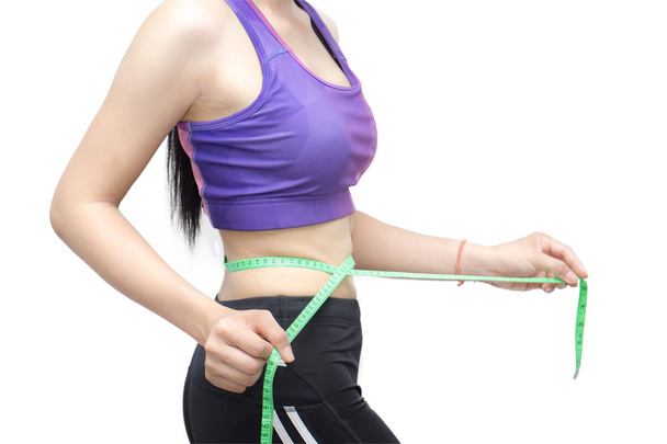 Woman in sport bra measuring her body with tape isolated on whit - Photo, Image