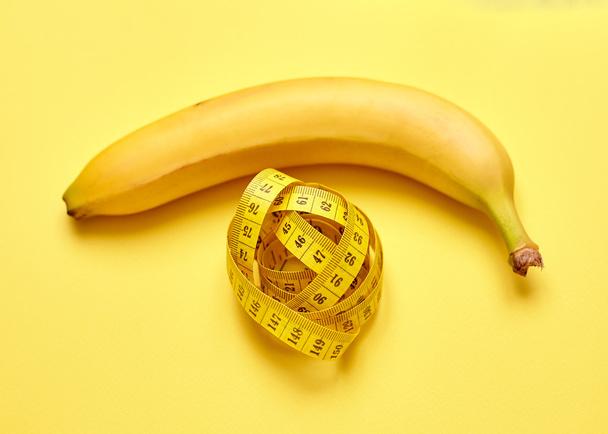Изолированный банан с измерительной лентой на желтом фоне
 - Фото, изображение