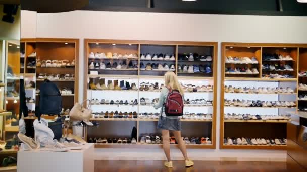 Η κοπέλα στο κατάστημα επιλέγει παπούτσια - Πλάνα, βίντεο