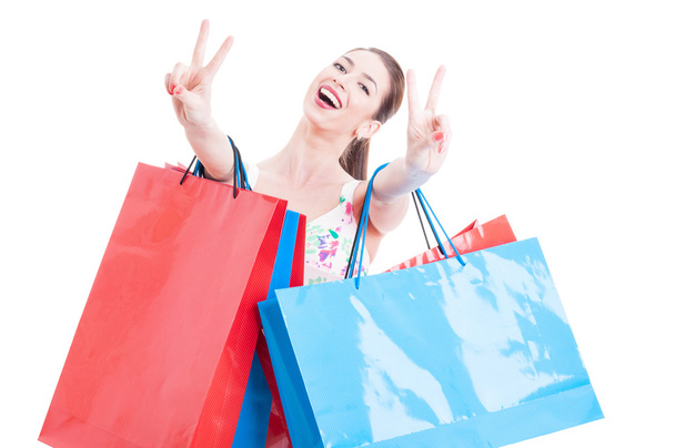 Woman at shopping with bunch of bags showing peace sign - Foto, afbeelding
