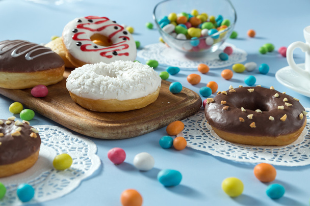 Donuts savoureux avec fruits et bonbons sur la table
 - Photo, image