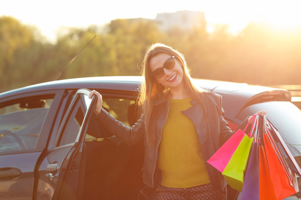 Усміхається жінка кавказька, поклавши її сумками в машину - Фото, зображення