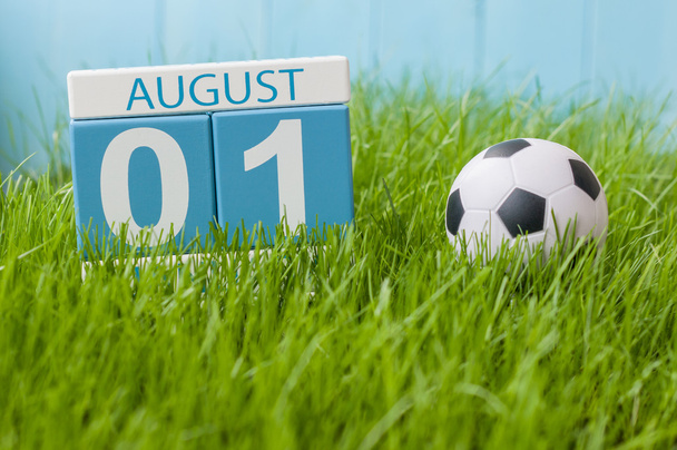 1. sierpień. obraz z drewna kalendarz drewniany kolor na zielonym trawniku tle z piłką nożną. Letni dzień. Puste miejsce na tekst - Zdjęcie, obraz