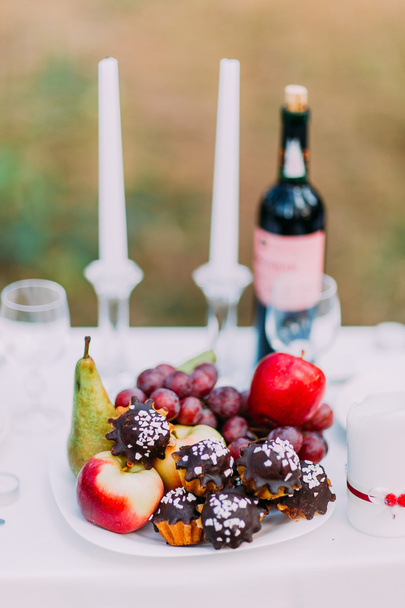 Outdoor romantic dinner table settings with wine, glasses, sweets and candles - Foto, Bild