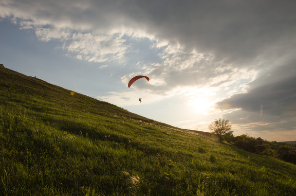 Silhouette de parapente volant dans le ciel avec des nuages dans une lumière du lever du soleil. Vallée des Carpates ukrainienne
. - Photo, image