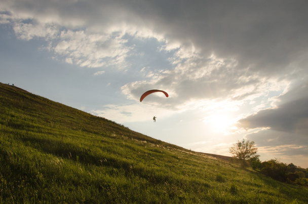 Silhouette of paraglide flying in the sky with clouds in a light of sunrise. Ukrainian Carpathian valley. - Fotografie, Obrázek