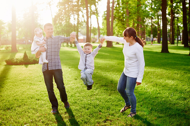 ευτυχισμένος νεαρή οικογένεια βόλτες στο πάρκο καλοκαίρι - Φωτογραφία, εικόνα