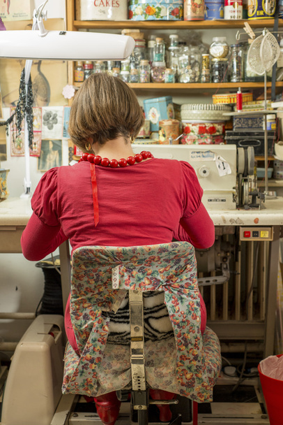 Seamstress Seated and Working on Sewing Machine - 写真・画像