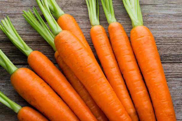 Fresh carrots bunch on rustic wooden background. - Photo, image