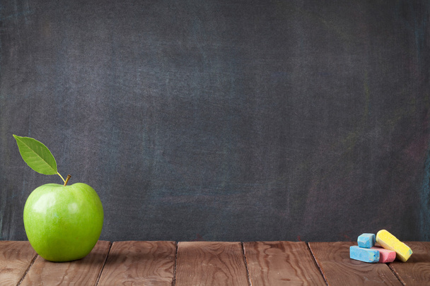 Яблочные фрукты и мел на школьном столе
 - Фото, изображение