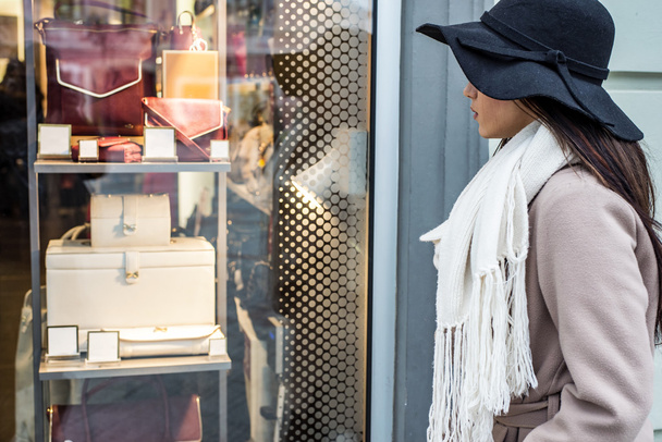 Молодая женщина смотрит в витрину магазина
 - Фото, изображение