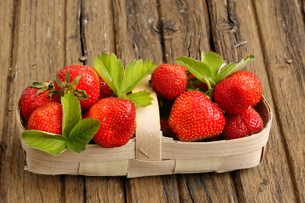strawberries in a basket on an old shabby wooden background rustic retro style - Фото, зображення