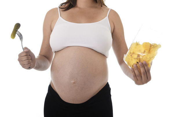 młode atrakcyjne kobiety w ciąży, Wyświetlono duży brzuch jedzenie chipy gospodarstwa marynacie z widelcem - Zdjęcie, obraz