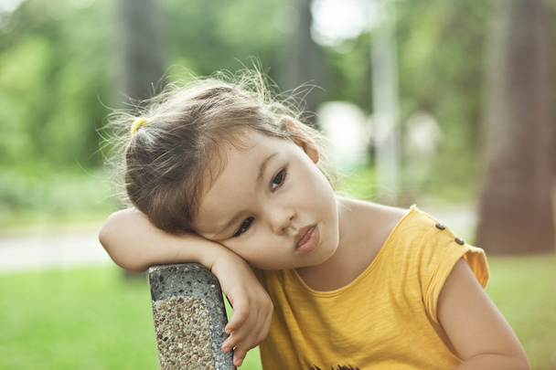 The little girl sits on a bench on vacation - 写真・画像
